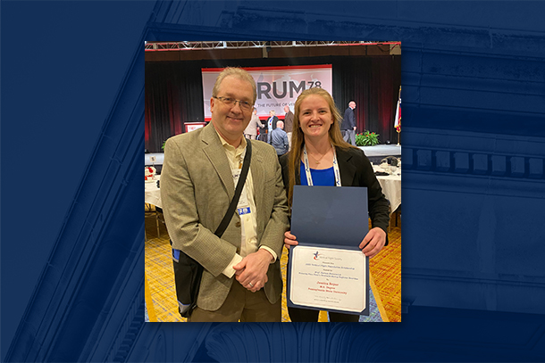 Man with glasses poses next to young woman holding certificate at business gathering.