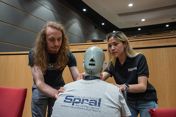 Man with long curly hair, beard and mustache and woman with blonde hair adjust dummy for experiment. 