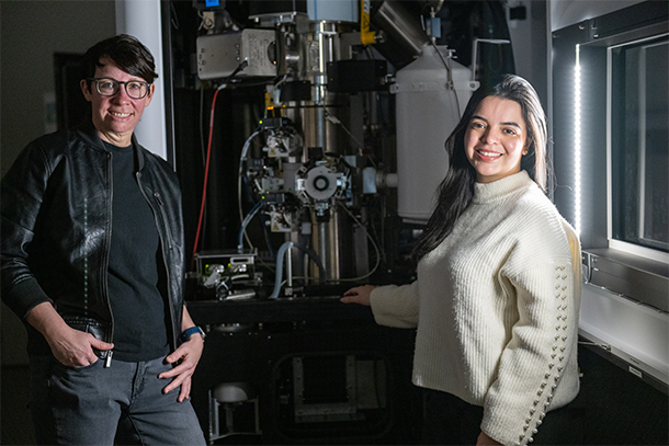 Two individuals stand next to a cryo-electron microscopy machine in a lab. 