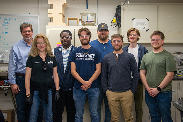 A group of students and two faculty pose in a laboratory for a group photo