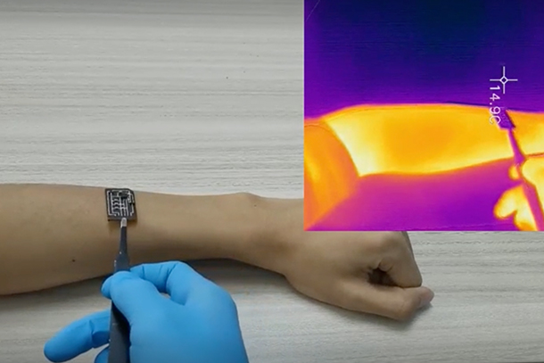 a gloved hand uses tweezers to place a small sensor on another person's forearm. A heat map of the forearm is shown in the upper right