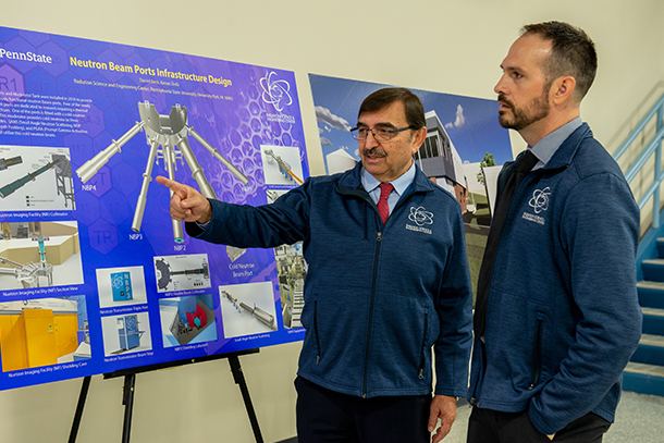 two people read a poster detailing a recent expansion of the Radiation Science and Engineering Center