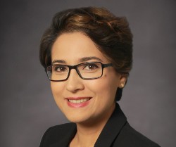 headshot of a person in glasses and a black blazer