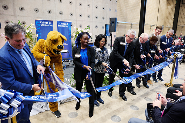 nine people cut a ribbon at a ribbon-cutting ceremony for a new building