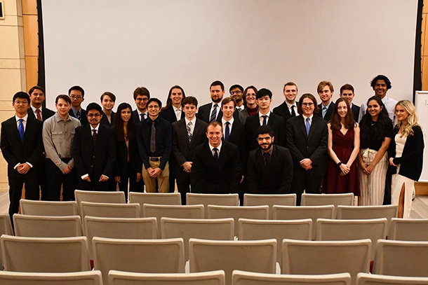 A group of formally-dressed students pose in an auditorium