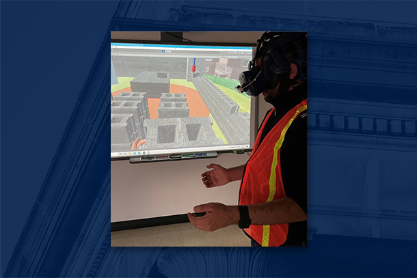 Individual dressed in construction gear stands in a classroom exploring a virtual reality construction site