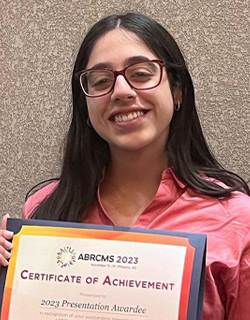 A person in glasses smiles while holding a certificate.