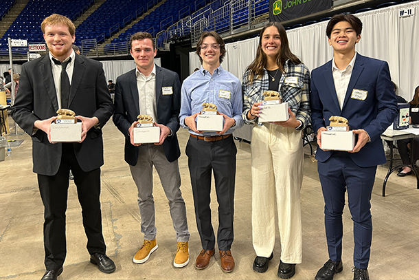 Five students, Dale Miller, Kieran Meehan, Taylor Casavant, Sydney McKernan and James Fong, stand in a row, all holding award statues of the Penn State Nittany Lion