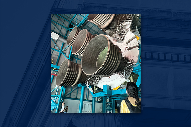 An individual looks at the exhaust pipes of a rocket on display