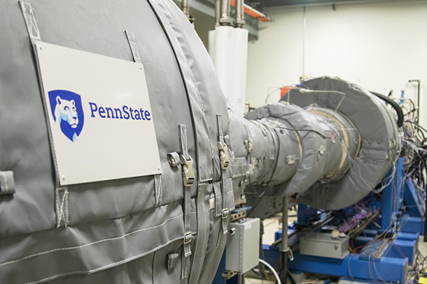 A large piece of machinery wrapped in grey padding with a penn state sign on it. 