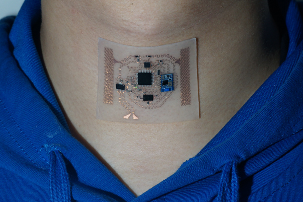 A wearable medical sensor is seen on an individual's neck.