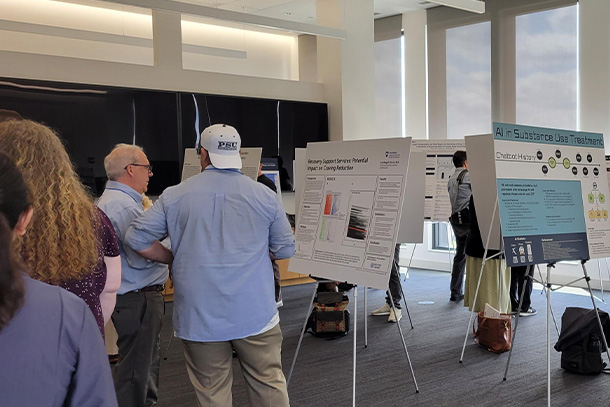 several people stand looking at research posters during consortium.