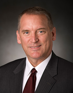 A headshot of an individual wearing a suit and tie.