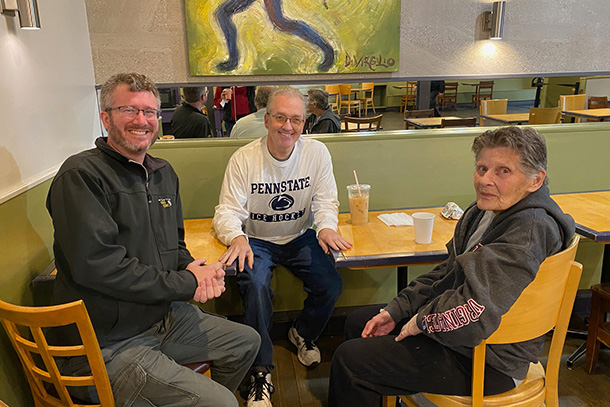 Three individuals sit around a table in a coffee shop.