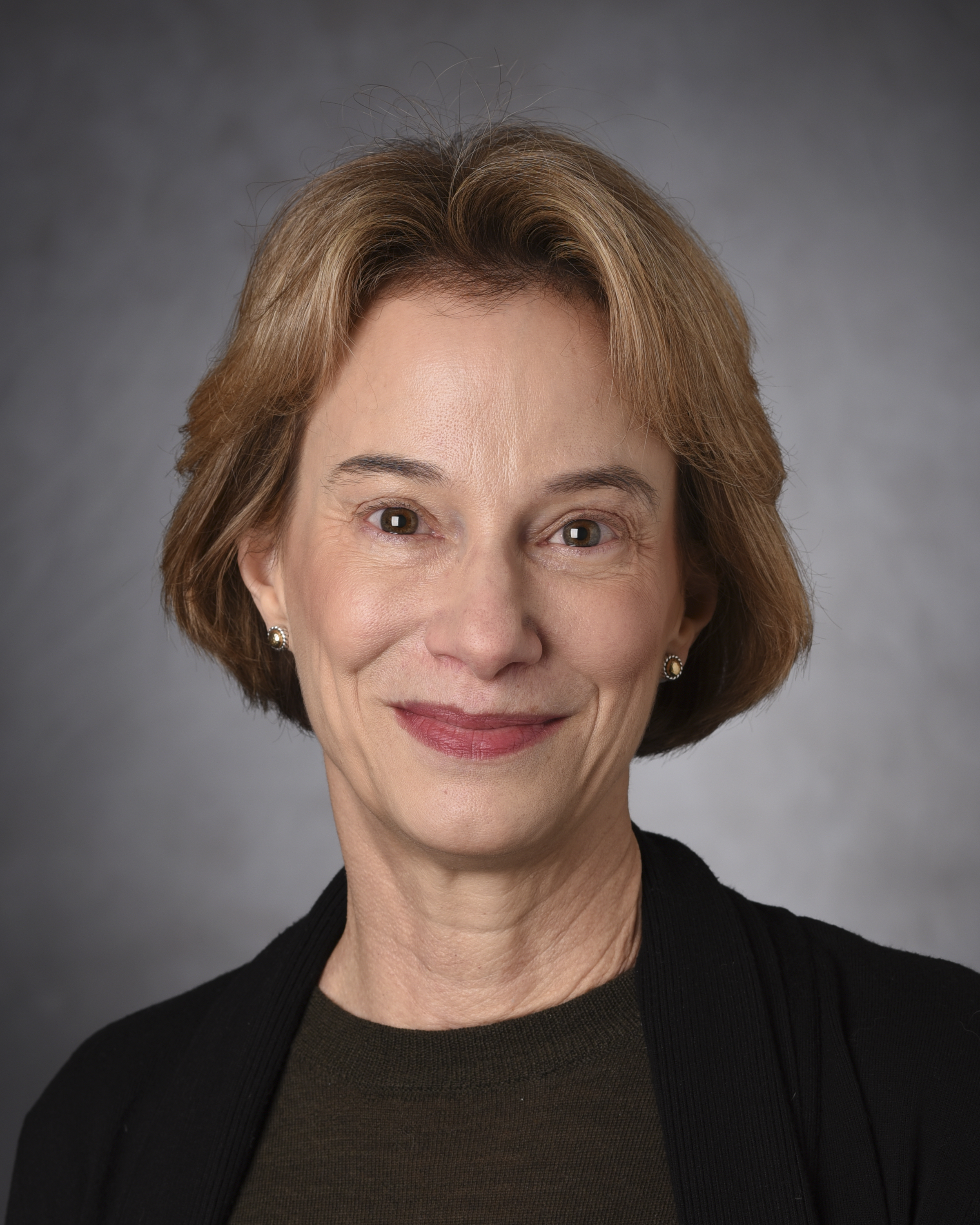 A professional headshot of an individual on a gray background. 