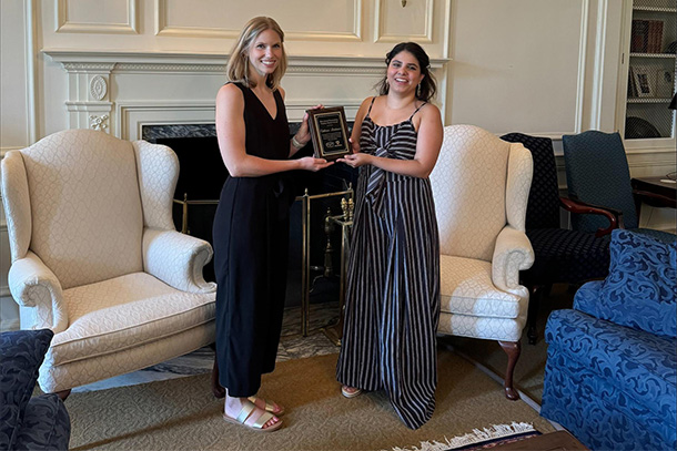 two women stand posing with award