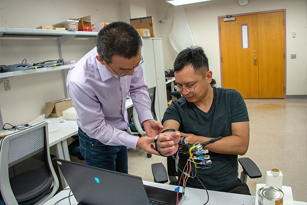 Two people adjust a prosthetic hand.