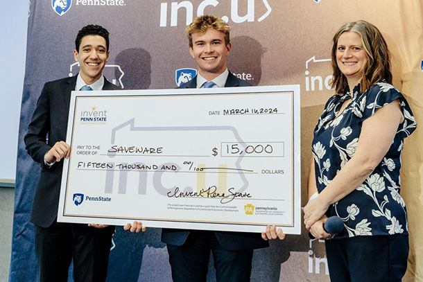 Three individuals holding a giant check in front of a backdrop.