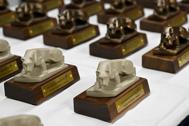 Trophies depicting the Nittany Lion are arranged on a table.