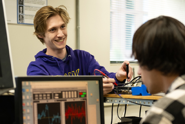 Two students look over a computer to test semiconductors in a lab.