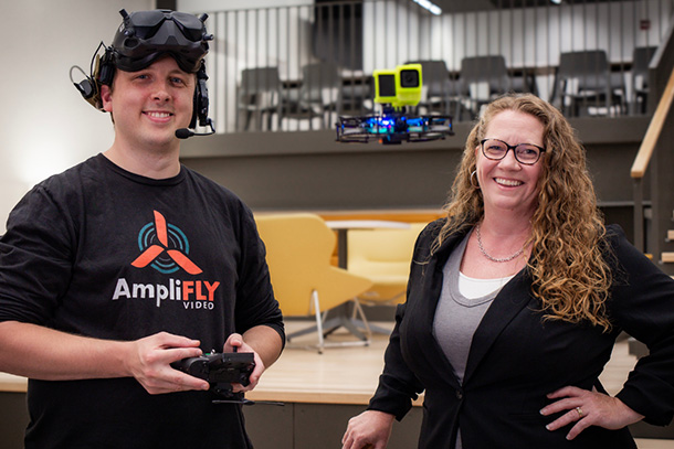 Two individuals in front of a table, one is wearing VR equipment