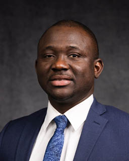 A headshot of a person wearing a suit and tie