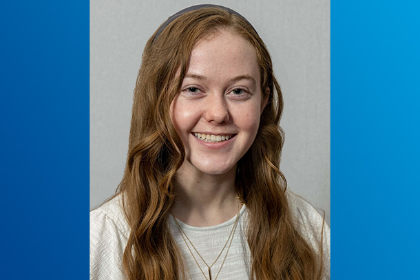 A headshot of an individual on a blue background. 