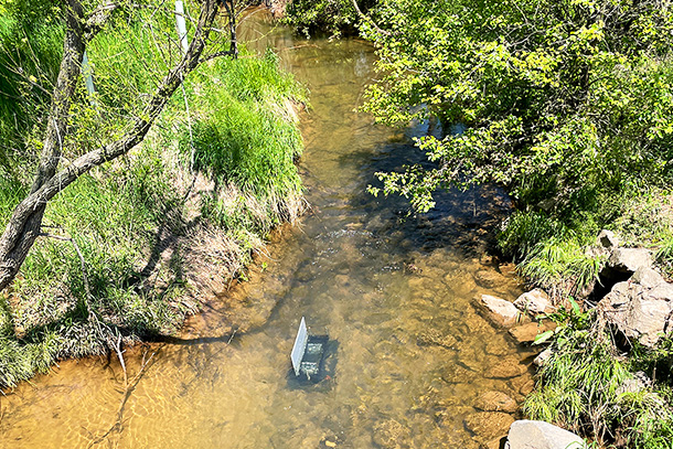 view of stream and trees with equipment in water