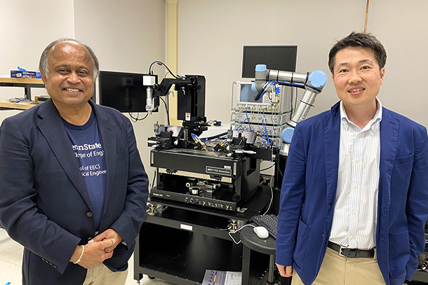 two individuals pose for a photo in front of lab equipment.