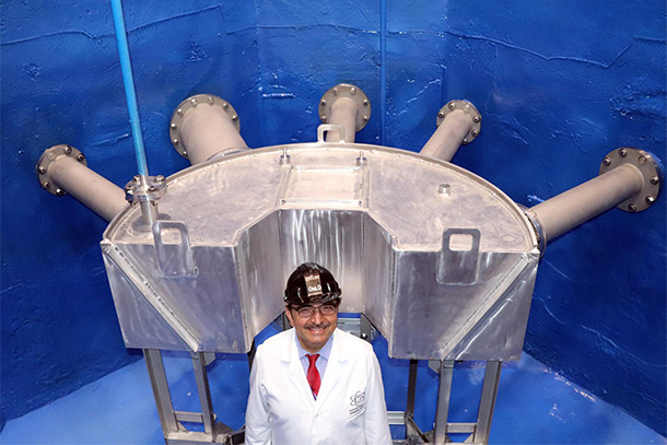 person in hard had standing and smiling in front of nuclear reactor. 