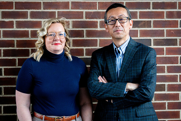 From left, Nikki Crowley and Nanyin Zhang pose for a photo in front of a red brick wall.