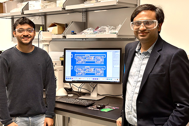 Two people stand in a lab with a computer display between them