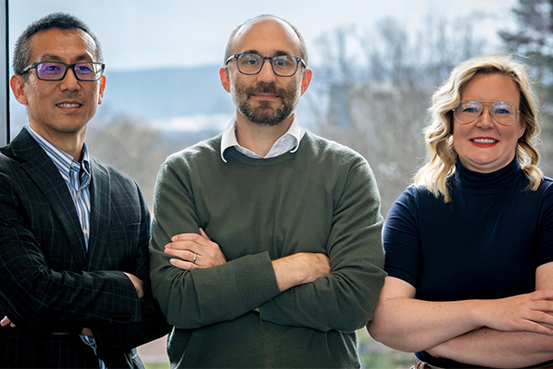 Three people crossing their arms pose for a photo.