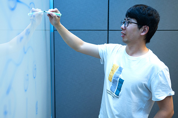 A student writes on a whiteboard.