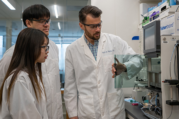 researchers in lab coats standing in a lab