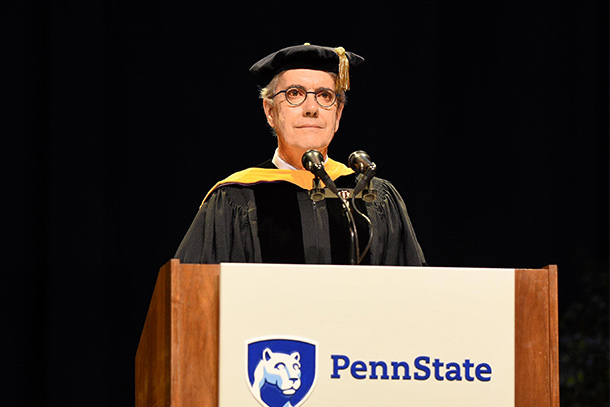 An individual wearing academic regalia stands at a podium.