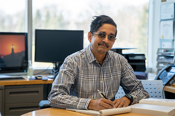 Man sitting at desk smiling at the camera.  