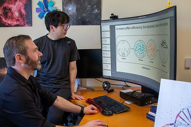  Two individuals look at a computer screen in an office setting.