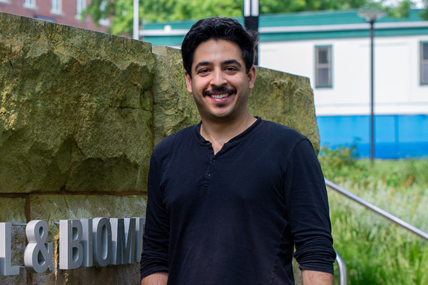 Associate professor poses for headshot next to Chemical and Biomedical Engineering Building sign on Penn State's University Park campus.