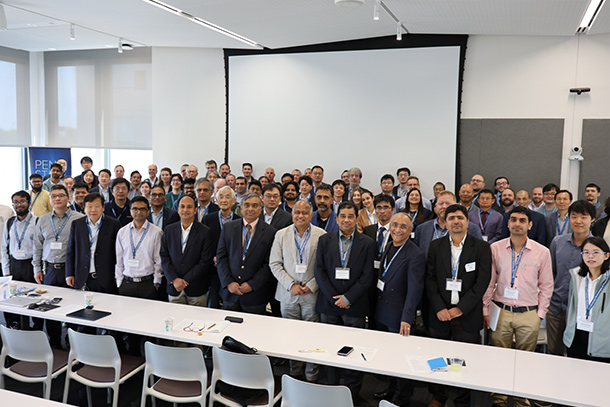 A group of people stand in a large conference room.