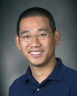 male professor in business attire smiles and poses for professional headshot photo
