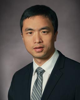 headshot of a man wearing a suit and tie